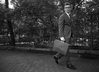 A man in a suit walking with a briefcase embodies the rules of the Art of Manliness.