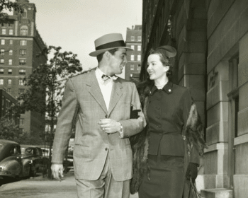 An old black and white photo of a man and woman strolling down the street on a perfect first date.