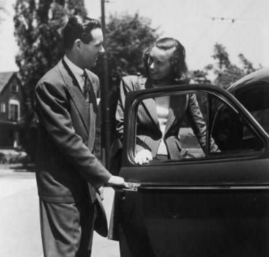 Vintage man opening door of car for woman.