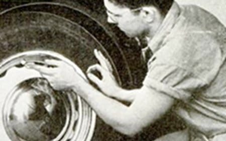 A man rotating the tires of a car.