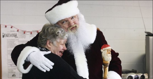 A Santa Claus is embrace an elderly woman in a heartwarming moment.