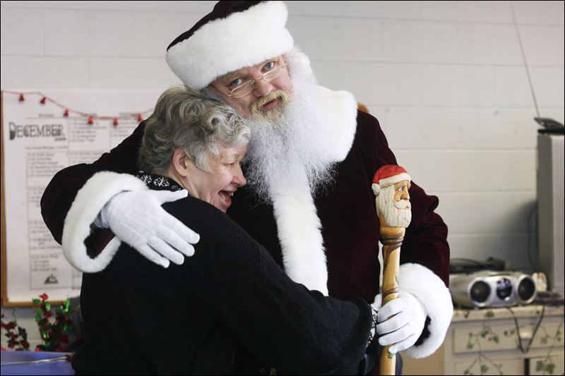 A Santa Claus is embrace an elderly woman in a heartwarming moment.