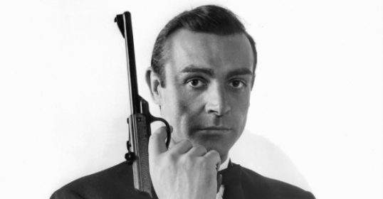 A man holding a gun in a black and white photo.