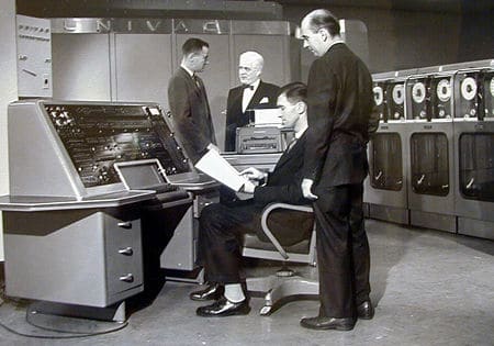 Vintage 1950s computers men in room programming.