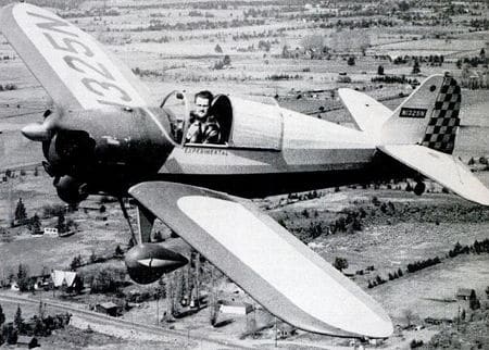 Vintage pilot in open-air cockpit aerial shot.