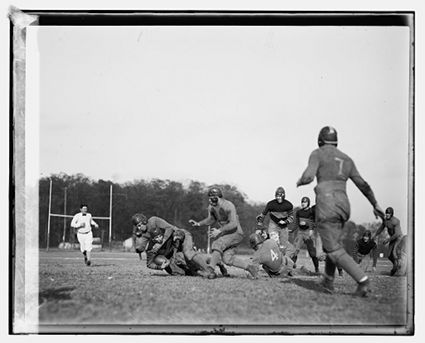 Vintage football players wearing helmets during game.