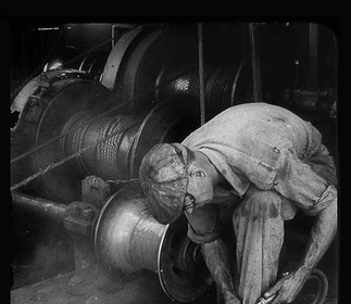A Manvotional black and white photo of a man working on a machine with hardihood.