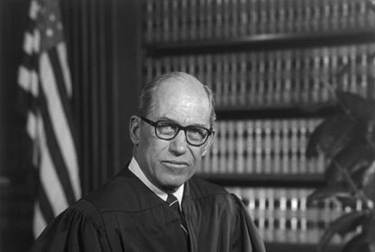 A black and white photo of a judge, showcasing manliness as he confidently sits in a chair.