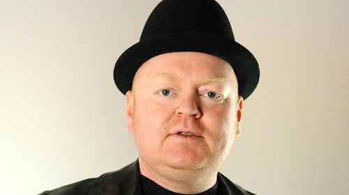 A freelance writer in a black jacket and hat.