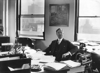 A man in a suit, managing business affairs at a desk.