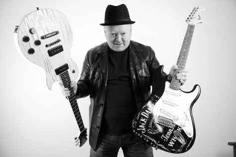 Edward Mitchell holding guitars in hands.