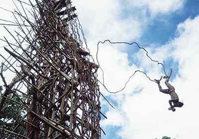A man is performing an insane jump from a tall wooden structure, undertaking a male rite of passage.
