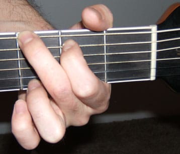 Man play string of guitar.