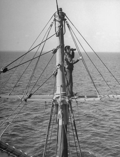 Man standing on nest ship and looking with binoculars.