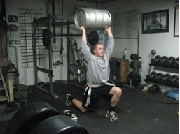 Man doing exercise of keg holding at gym.