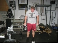 Man doing exercise by holding dumbbell and stone in hands.