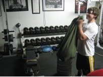 Man training with sandbag lifting at gym.