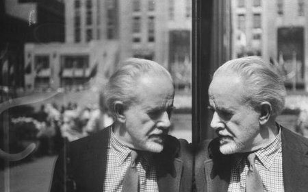 In this mesmerizing photograph, a dignified man in a suit finds himself captivated while admiring his own reflection in a window. The moment captures the essence of self-contemplation and