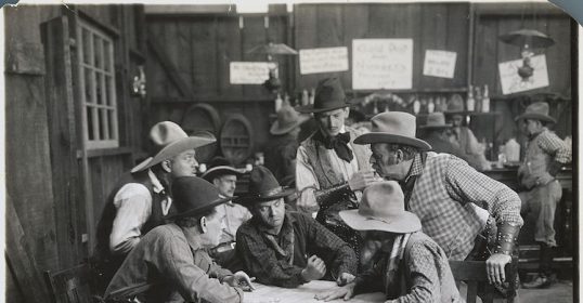 A group of manly cowboys sitting around a table.