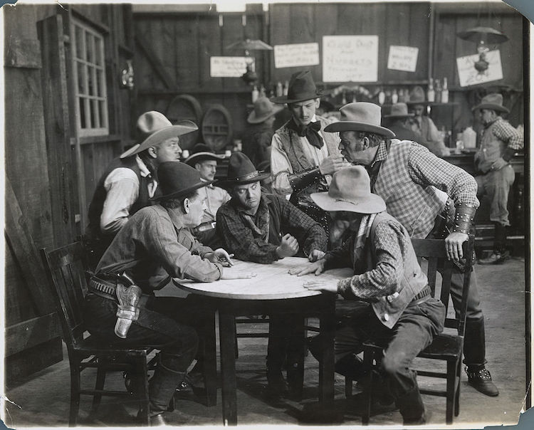 A group of manly cowboys sitting around a table.