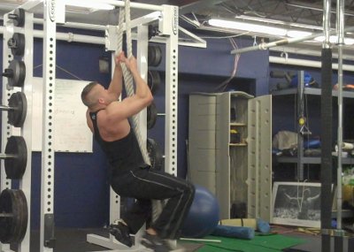 Heavy rope pull ups training by man in gym.