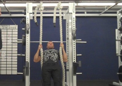 A man doing supine rows heavy ropes training in gym.