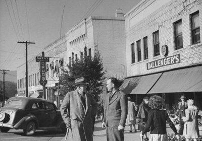 Two men, one of them holding a child, standing on a street corner and discussing the urgency to take action now.