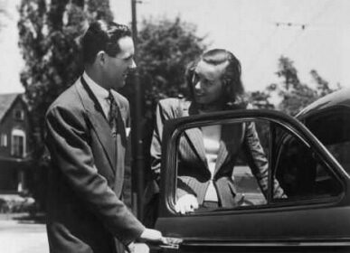 A gentleman helping a woman into his car on their first date.