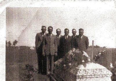 A group of men howling next to a casket as they plan a funeral.