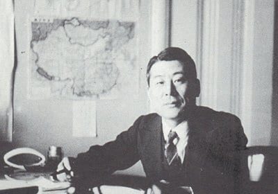 A man in a suit embodying manliness while sitting at a desk.