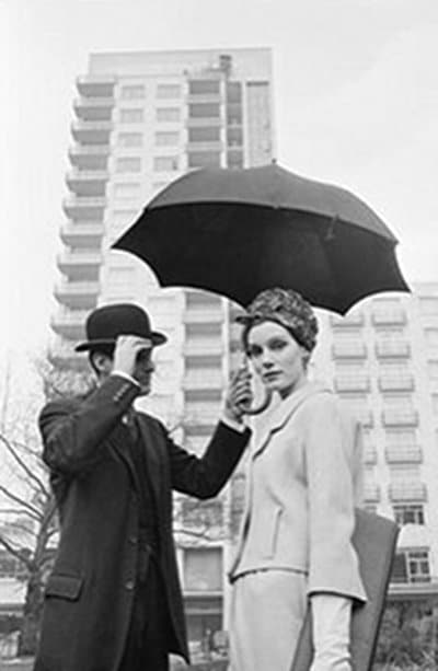 Mid vintage man holding umbrella for woman.