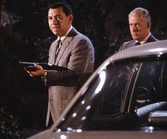 Two men in classic suits standing next to a car.