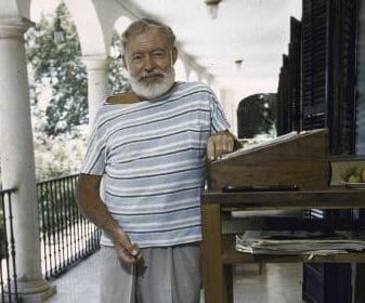 A man with a beard standing next to a table in summer.