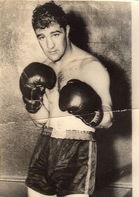 A black and white photo of a man in boxing gloves showcases his powerful stance and solid boxing basics.