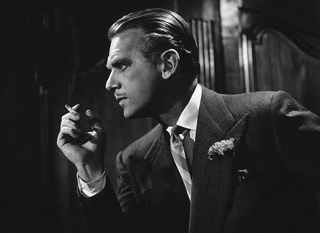 A vintage man in a suit with boutonniere holding a cigarette in hand. 