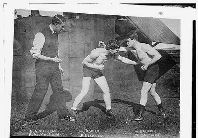 An old photo showcasing the basics of boxing with three men in boxing attire.
