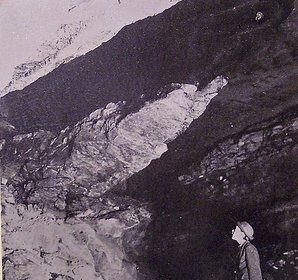 A black and white photo of a man standing in a rocky area, capturing the essence of the caving experience.