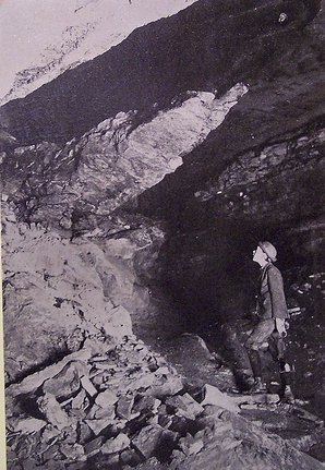 A black and white photo of a man standing in a rocky area, capturing the essence of the caving experience.