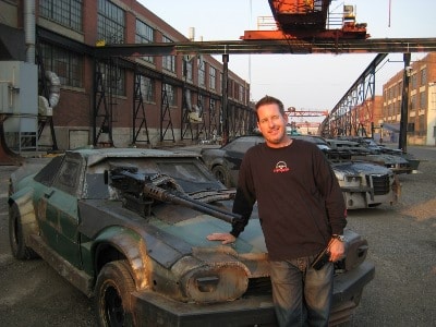 Greg tracy stuntman standing with death racing cars.