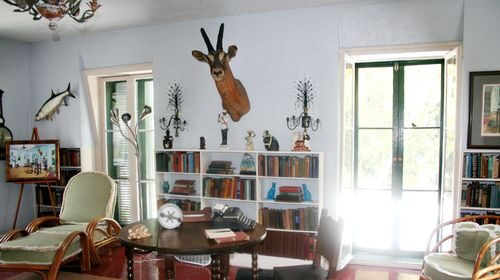 A famous man room with a table and chairs and a deer head on the wall.