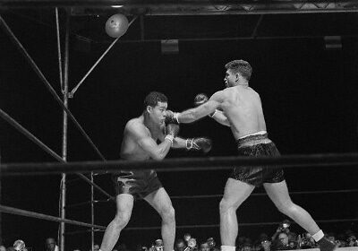 Two men in a boxing ring engaging in a punching battle.