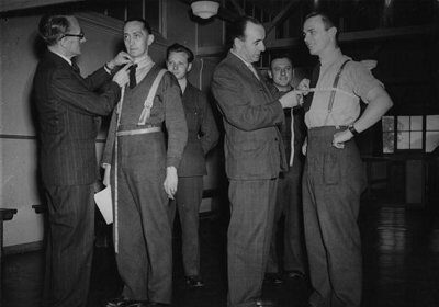 A group of men in tailored suits standing in a room, showcasing how precise personal measuring and clothing sizing can enhance their appearance.
