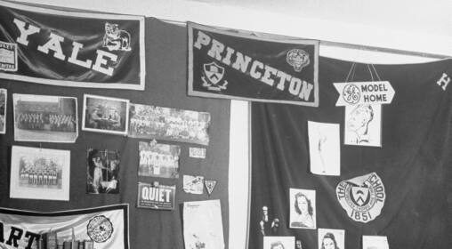 A group of men sitting in a room with a bed, protecting.