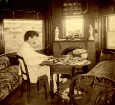 Mark twain busy in writing at table in the hut.