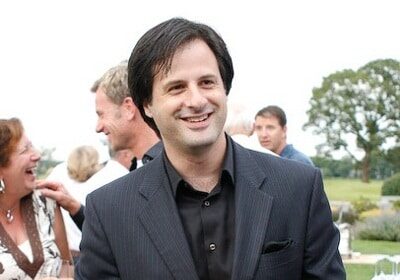 A magician in a suit smiling at an event.