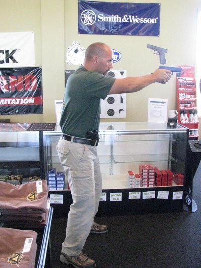 A man holding a position in gun store with his gun safely.