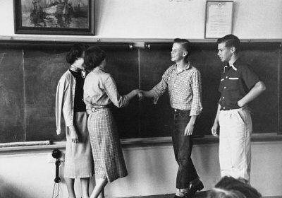 A group of gentlemen making introductions in front of a blackboard.