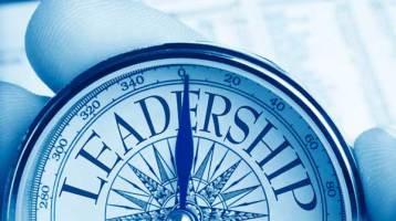 A person holding a compass inscribed with the word leadership, embodying the principles of Serve to Lead.