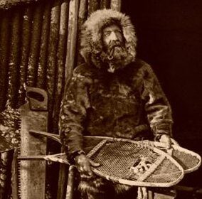 A man with a sled in front of a log cabin, embracing the Legends of the Northwest.