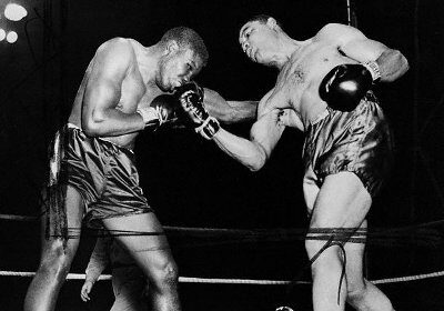A black and white photo capturing the intense punching action as two boxers engage in a gripping fight in a ring.